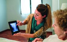 Female doctor showing to female senior patient in hospital an x-ray on the tablet