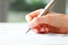 A woman's hand with pen writing on a form