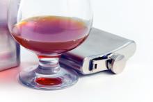 An alcoholic beverage in a glass near a flask
