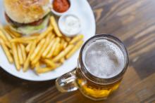 Beer in a mug with plate of fries and a burger