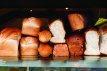 Loaves of fresh bread piled on a bakery counter.