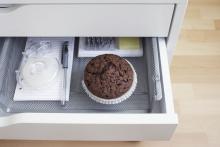 A chocolate muffin in an office desk drawer.