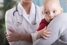 Woman holding baby and speaking with doctor.