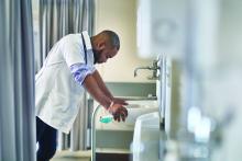 Distressed doctor leaning over sink in hospital room