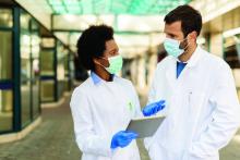 Two doctors talk while wearing masks