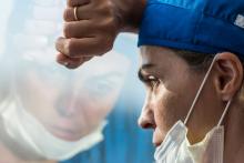 stressed female doctor with mask looking out a window