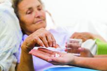 An older woman lying in bed takes medication.