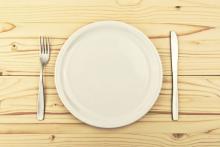 Fork, empty plate, and knife on a table.