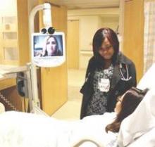 Hospitalist Dr. Dana Giarrizzi, pictured on screen, and nurse Tina Taylor care for a patient. “Telemedicine is just an extension of the telephone,” Dr. Giarrizzi says. “Now we’re just better at it. We’re able to put eyes on it rather than just ears.”