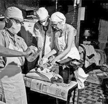 A teaching moment between Dr. Beatrice Tucker and a resident physician in the 1950s. Notice the baby on the kitchen table and medical student washing his hands in the kitchen sink.