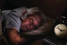 An elderly man lying in bed with insomnia.