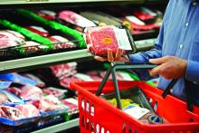 A shopper reads the label on a package of red meat.