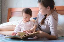 Mother reading a book to her child on the bed. Bedtime story. Learning how to read.