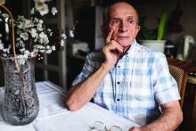 Old man sitting at a table with serious face expression