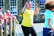 Girl who is overweight, with schoolmates on playground