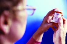 A woman reads the label on a pill bottle.