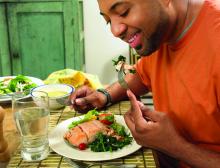 A man enjoys a dinner of salmon and vegetables