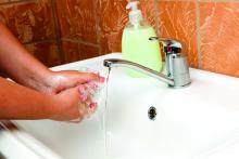 A woman is shown at a sink washing her hands.