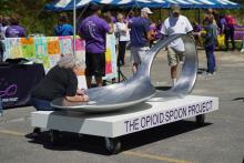 Women signing the Opioid Project's spoon sculpture