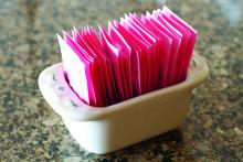 A container holds packets of artificial sweeteners