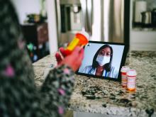 A senior aged woman in her home, talking to a doctor online in a virtual appointment.