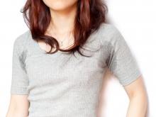 A young woman with grey shirt with sweat on her under arms. 