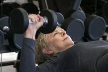 Woman with grey hair lifting hand weights at gym