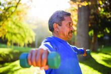 Mature man exercising with dumbbell on sunny day at park