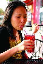 Young Asian Woman Drinking Cranberry Juice at Sidewalk Cafe