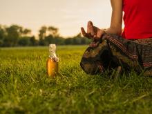 Woman meditates next to a bottle of beer