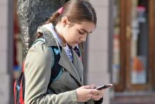 A young woman looks at her smartphone.