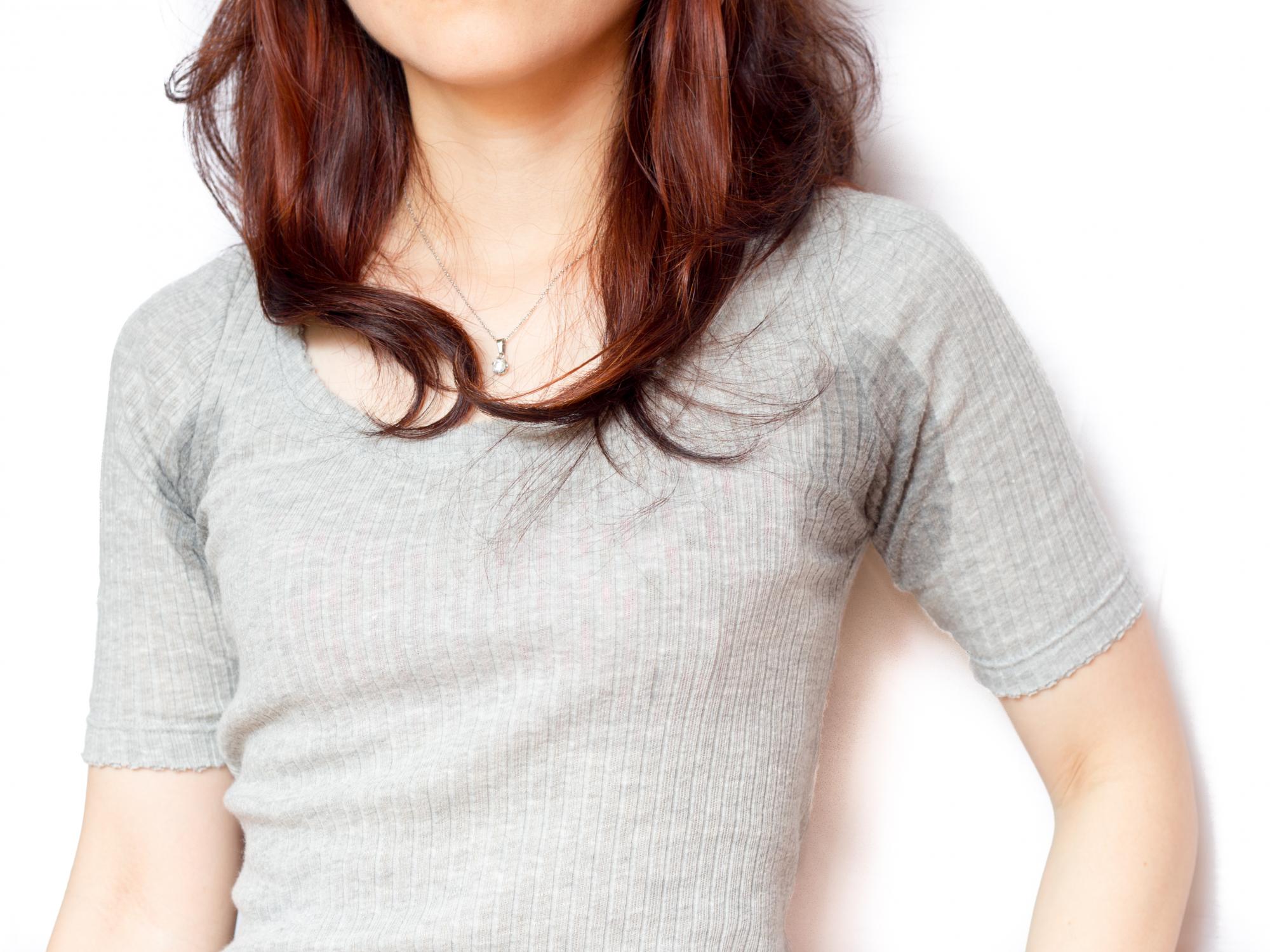 A young woman with grey shirt with sweat on her under arms.